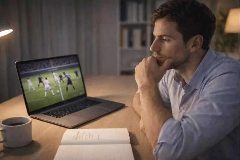 Uomo concentrato che studia partite di calcio su un laptop in ambiente domestico